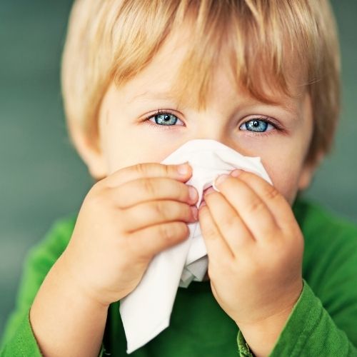 Young boy using a tissue on his nose